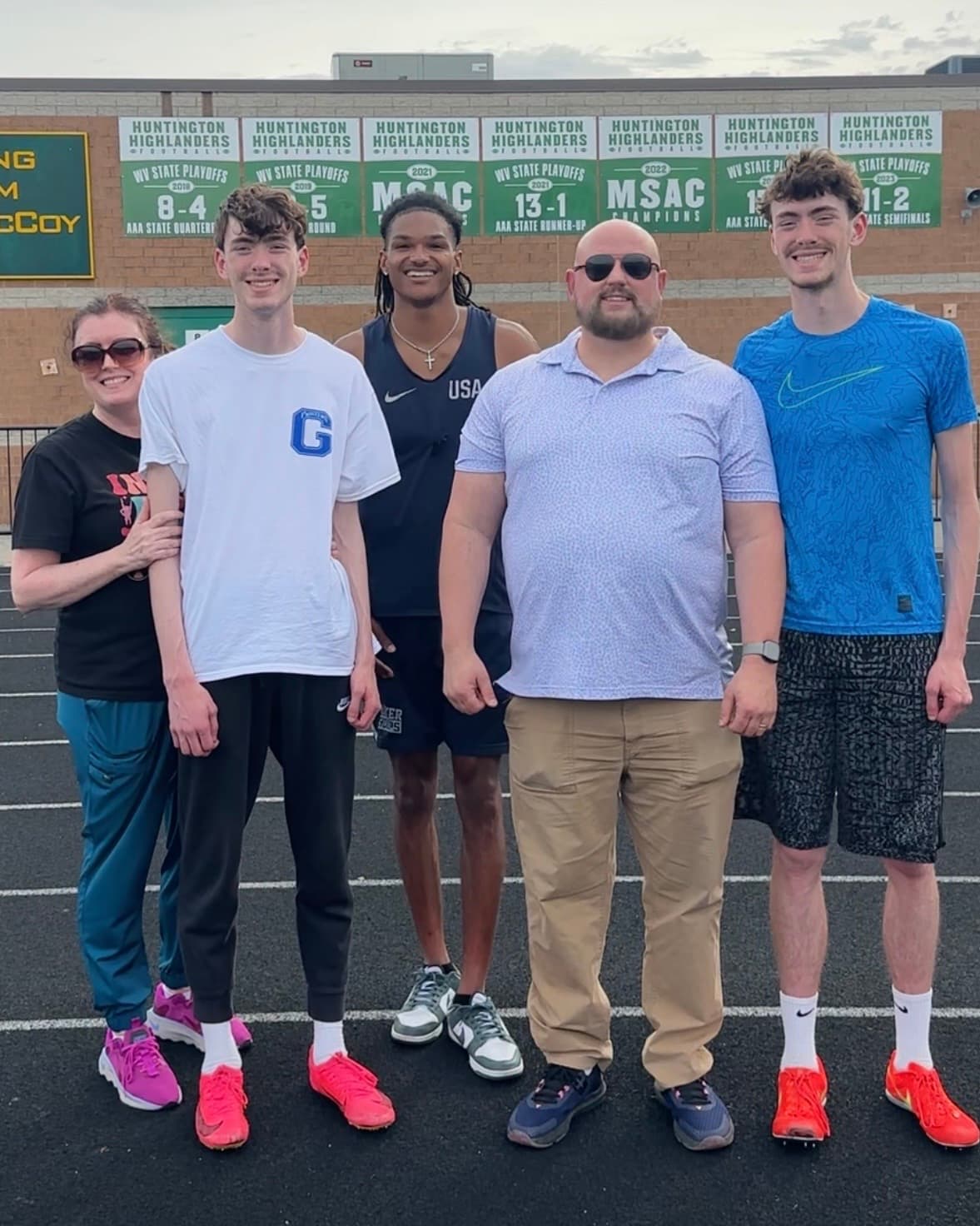 Coach Dontavious Hill at center with two athletes and their parents trackside